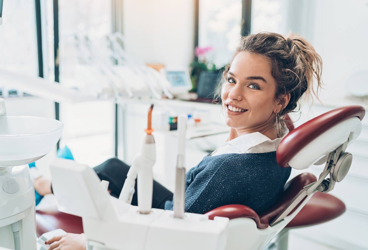 Brunette woman smiles while sitting in the dental chair to take control of her oral health