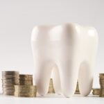 A tooth surrounded by piles of coins to represent dental insurance