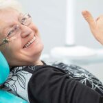 senior woman smiles and gives up thumbs up in the dental chair