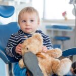 young boy holding a teddy bear in the dental chair