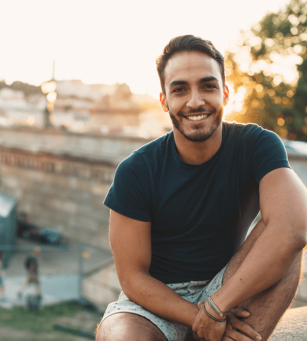 man in black t-shirt smiling in front of a sunset