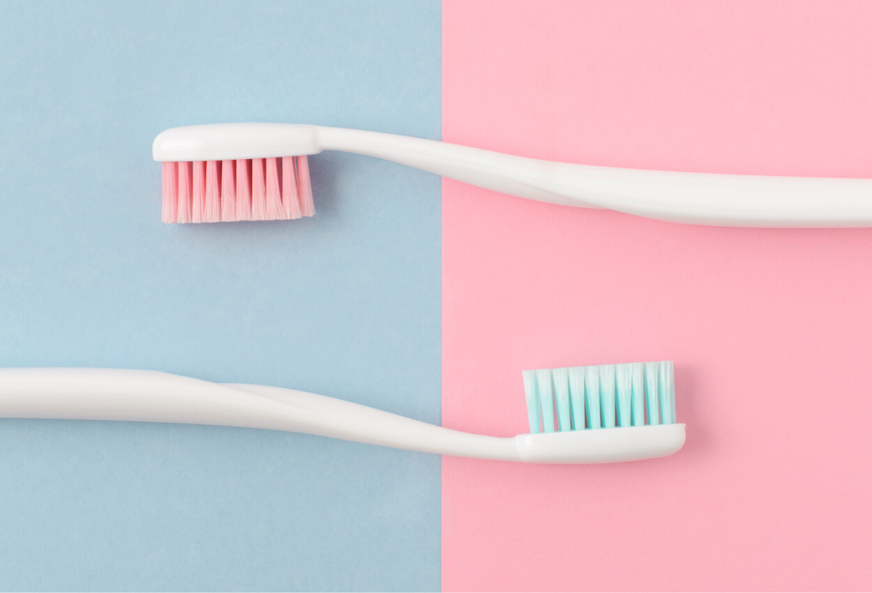 Aerial view of two toothbrushes against a purple and pink background