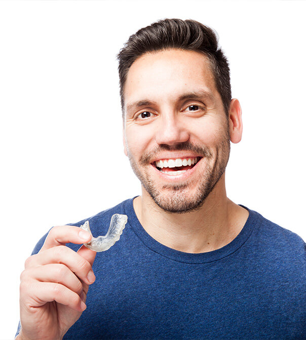 dark haired man smiling and holding clear aligner