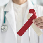 closeup of a dentist holding a red and beige ribbon for Oral Cancer Awareness Month